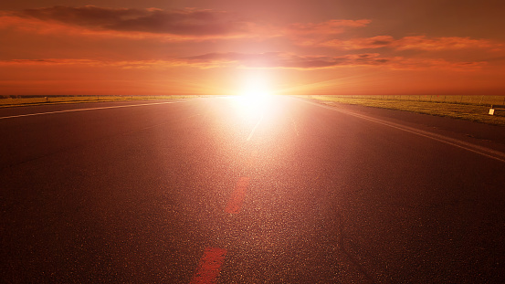 Long empty asphalt road towards sunset sun