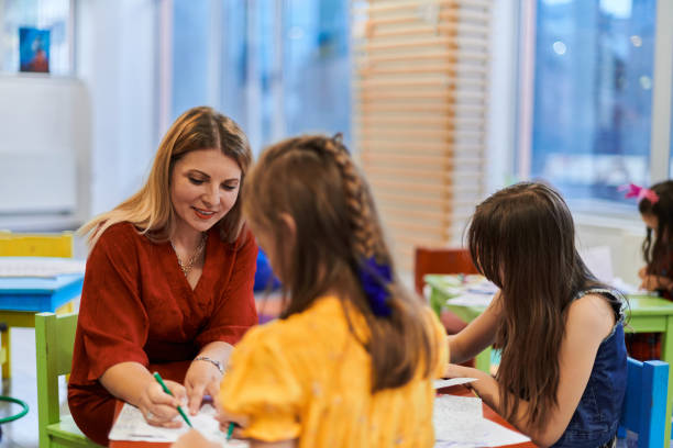 istock Creative kids during an art class in a daycare center or elementary school classroom drawing with female teacher. 1490465302