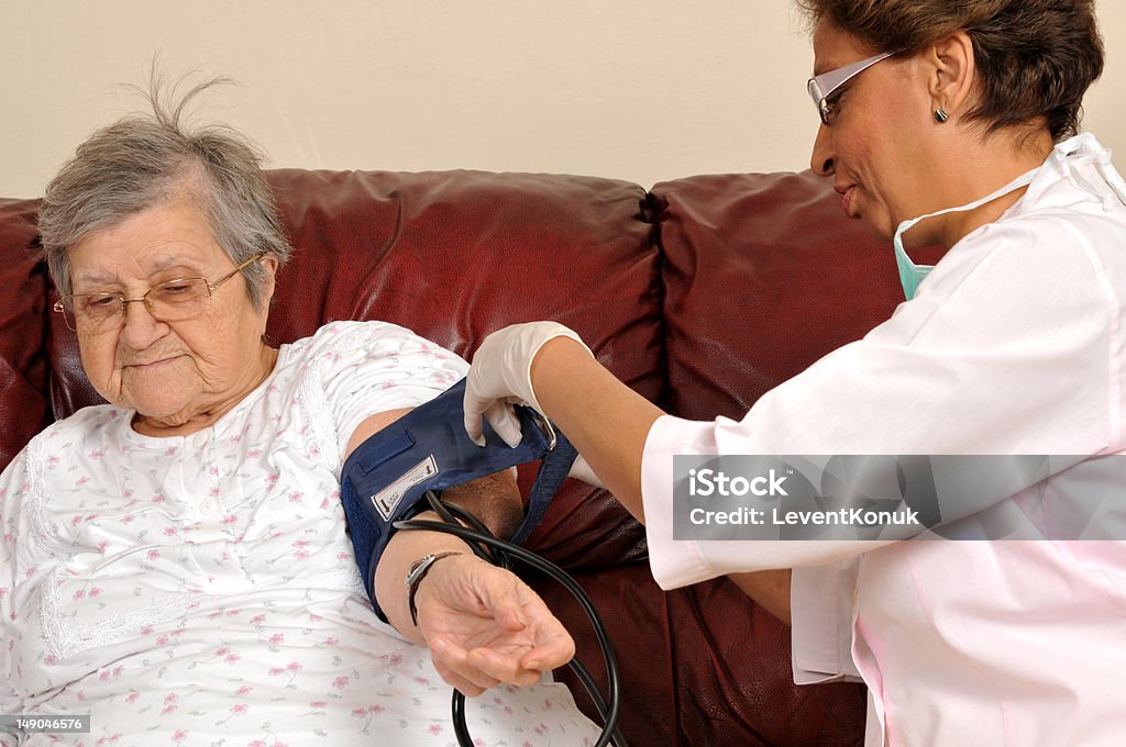 Blood pressure Mixed raced nurse measuring senior patient's blood pressure - a series of MEDICAL IMAGES. Adult Stock Photo