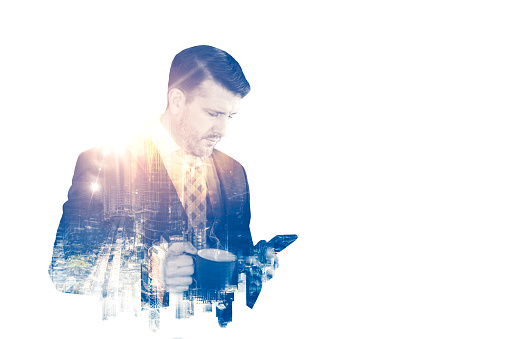 The double exposure image of the business man standing holding a mobile phone and a cup of coffee during sunrise overlay with cityscape image
