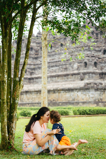 asian woman with her son sitting  on the grass with Borobudur temple in the background