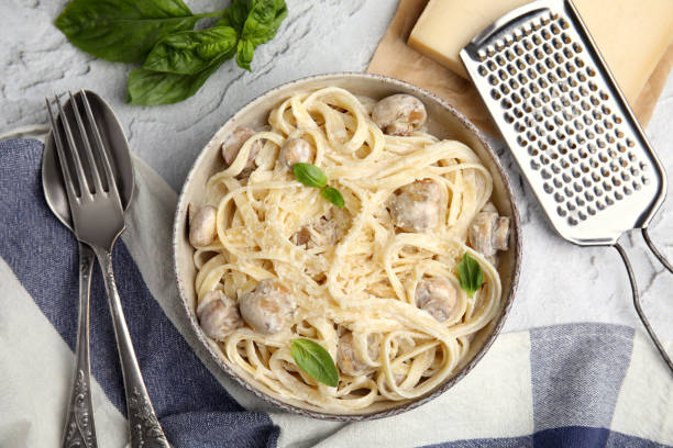 istock Delicious pasta with mushrooms and cheese served on light grey textured background, flat lay 1490469281