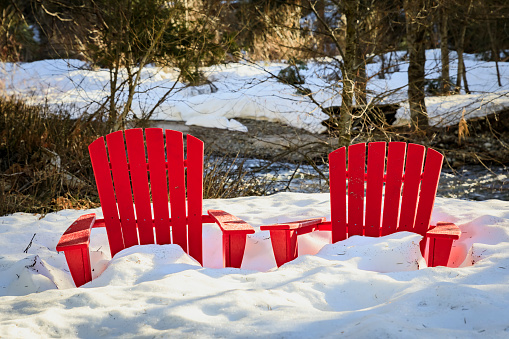 Red Adirondack Chairs covered in snow in a meadow in the Yosemite National Park, Sierra Nevada mountain range in California, USA