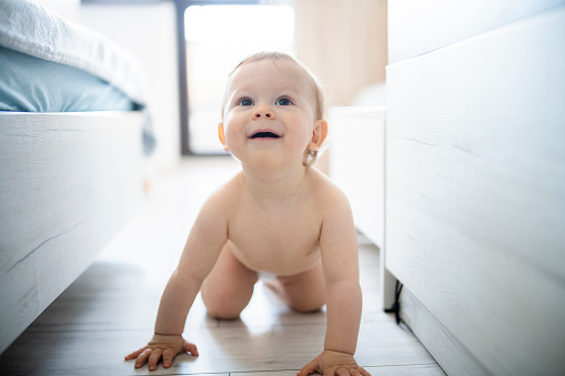 Cute and charming baby boy crawling on the floor.