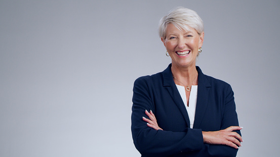 Portrait of a successful aged caucasion blonde woman wearing formal attire isolated over grey background