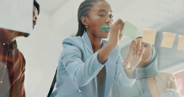 istock Team, employees and black woman brainstorming, sticky note and conversation in workplace. Teamwork, staff and group in office, planning and project plan for startup, ideas and innovation with goals 1490475893