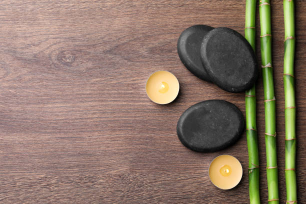 istock Spa stones, burning candles and bamboo stems on wooden table, flat lay. Space for text 1490476812