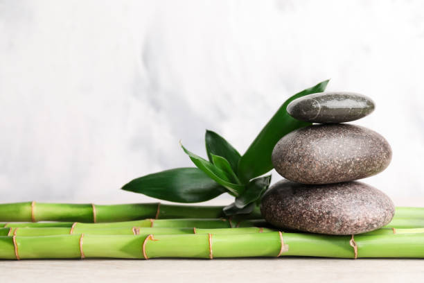 istock Stacked spa stones on bamboo stems against light blurred background. Space for text 1490477063