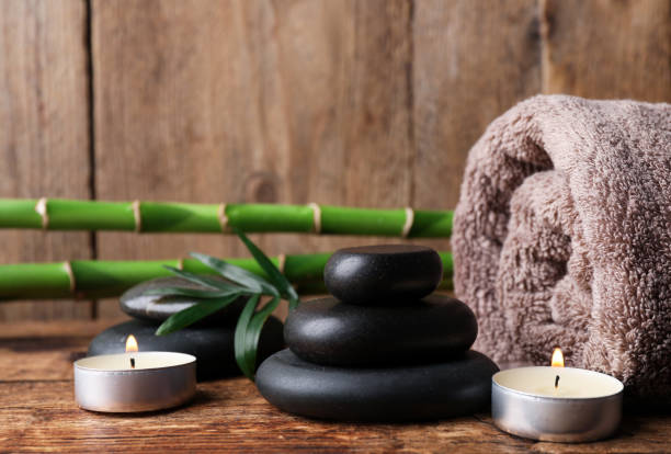 istock Stacked spa stones, bamboo, candles and towel on wooden table. Space for text 1490477128