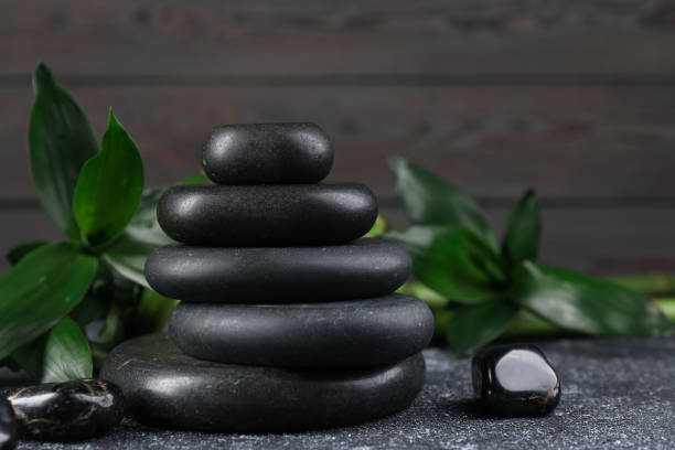 istock Stacked spa stones and bamboo leaves on black textured table, closeup 1490477255