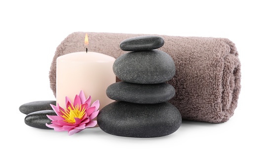 Stack of spa stones, towel, flower and candle isolated on white