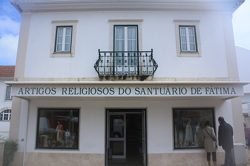 People entering a store selling religious and Catholic products. The photo was taken in Portugal in the city of Fátima.