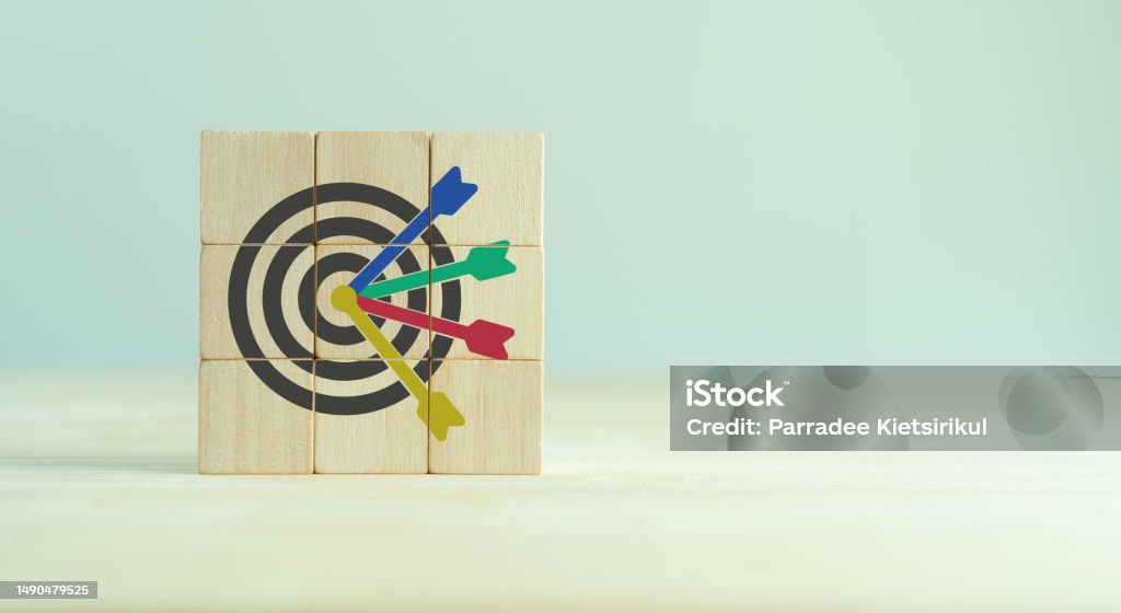 Targets, Goals, Objectives, KPI, OKR, business success, planning, goals achievement concept. Archery target ring with many targets and four arrows hitting the center of the objective on wooden blocks Accuracy Stock Photo