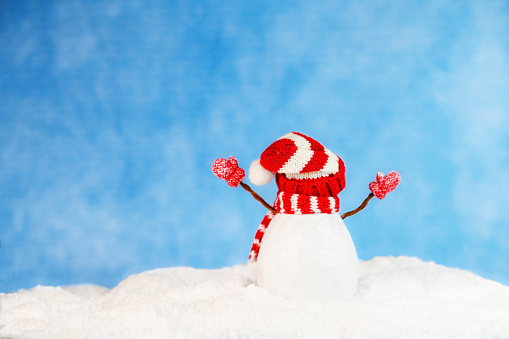 Cheering snowman with blue snowy background that has copy space. Can be used for winter holiday storytelling, Christmas cards, new year cards, advertisement and marketing. Studio shot. Not AI