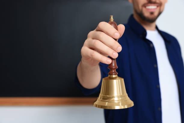 istock Teacher with school bell near black chalkboard, closeup. Space for text 1490487017