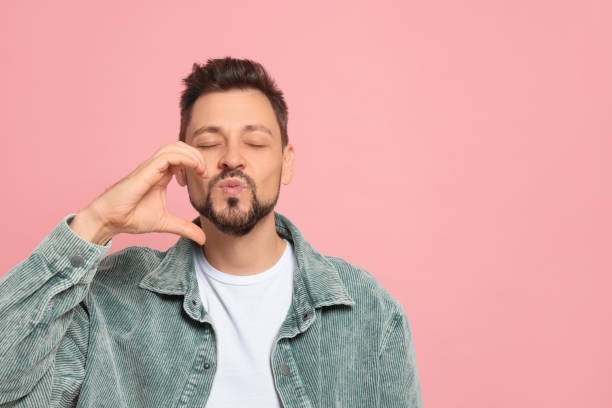 istock Handsome man blowing kiss on pink background. Space for text 1490487401
