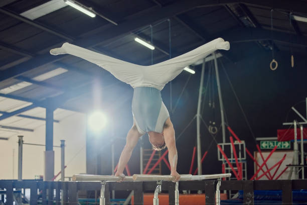 istock Gymnastics, exercise and workout with a man gymnast training on a bar in a gym or studio. Fitness, sports and health with a male athlete practicing on high bars for a competition 1490488673