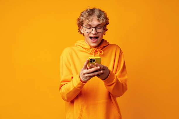 istock Happy caucasian young man using smartphone against yellow background 1490490191