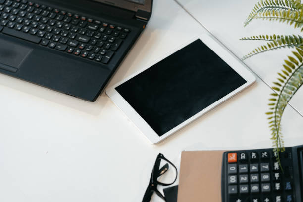 Laptop computer, digital tablet and calculator on office desk close up