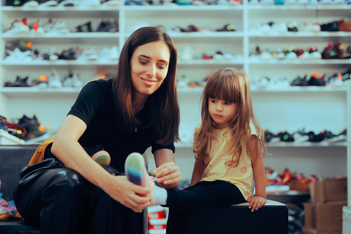 Mom helping her little girl finding well-fitting sneakers