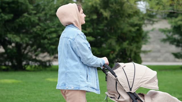 Adult woman walks with sleeping daughter in baby cradle