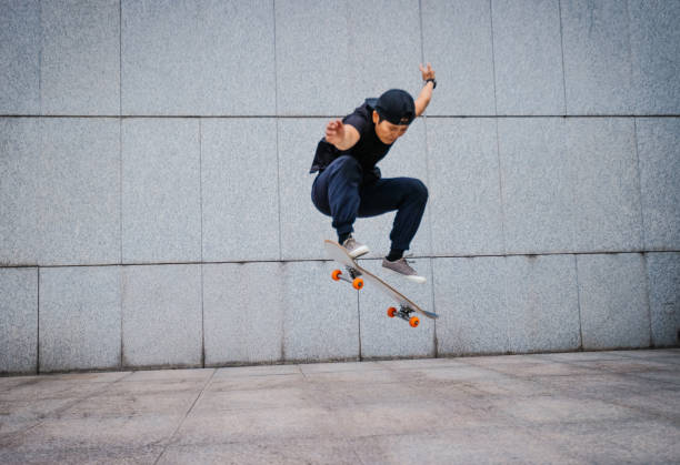 azjatka skateboarder skateboarding w nowoczesnym mieście - ollie zdjęcia i obrazy z banku zdjęć