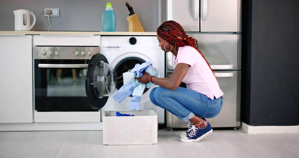 istock Young Woman Putting Clothes Into Washing Machine 1490497345