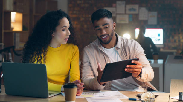 istock Night, office or people with tablet speaking of networking overtime on digital marketing plan at desk. Laptop, teamwork or employees talking about online project deadline data on internet late 1490497564