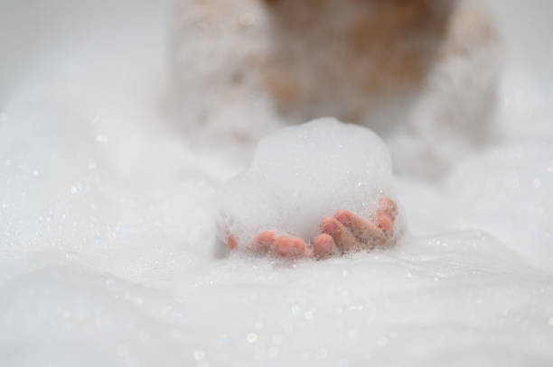 Close-up bubble foam on boy hands surrounded by soap suds when taking a bath in bathtub. Funny, healthcare lifestyle and hygiene concept