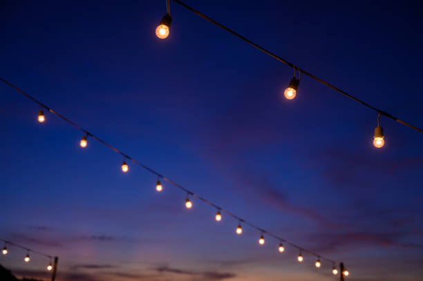 istock Festoon string lights decoration at the party event festival against sunset sky. light bulbs on string wire with copy space. Outdoor holiday background. 1490498024