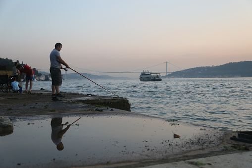 Istanbul, Turkey - July 19: Amateur fisherman is fishing on Cengelkoy Coastline at sunset on July 19, 2018 in Istanbul, Turkey.