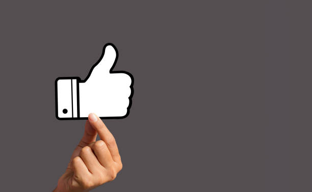 istock Hand holding a thumbs up a symbol against a gray background 1490519023