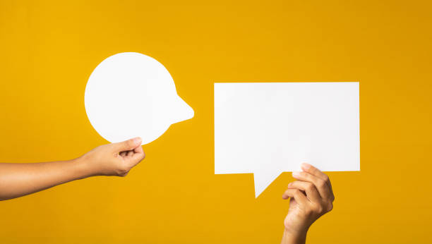 istock Hand holding of an empty white speech bubble against a yellow background. 1490519556