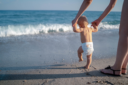 Mother and baby feet walking on sand beach