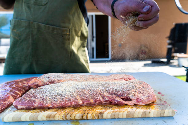 surowy stojak żeberek doprawia się suchym pocieraniem i pozostawia do marynowania. następnie jest powoli gotowany na grillu węglowym na podwórku, aż będzie miękki i zadymiony. - rubbing spice rib barbecue zdjęcia i obrazy z banku zdjęć