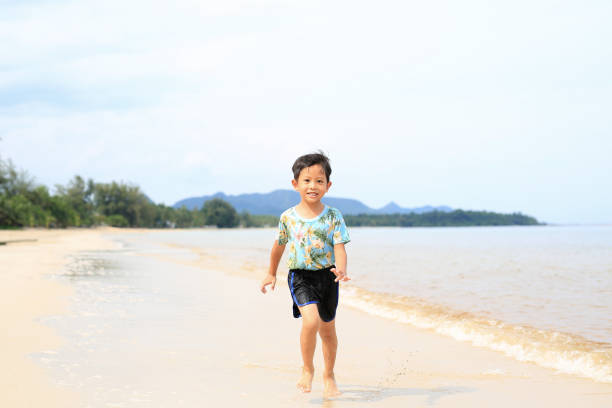 istock Asian little boy having fun running on tropical sand beach. 1490524609