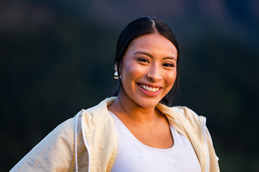 A hispanic  woman stands in the Columbia River Gorge Scenic area of Oregon, at Sunset. Medium head/shoulders portraits shot with a 135mm lens to create telephoto compression. Shot in Oregon, Pacific Northwest.