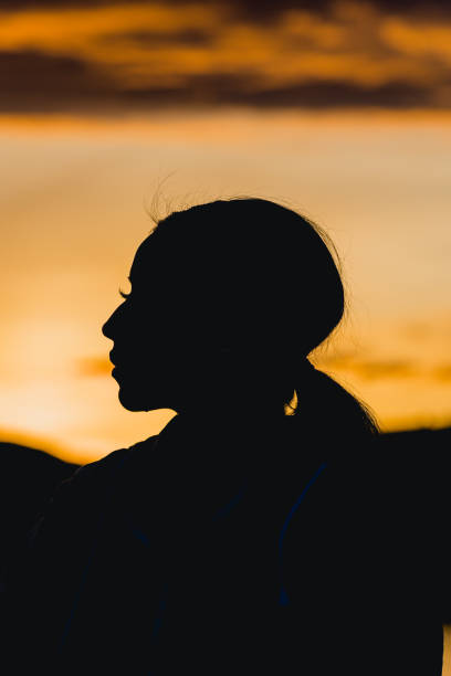 Woman enjoying sunset over the sea on the beach near her car. Travel, road trip and tourism concept.