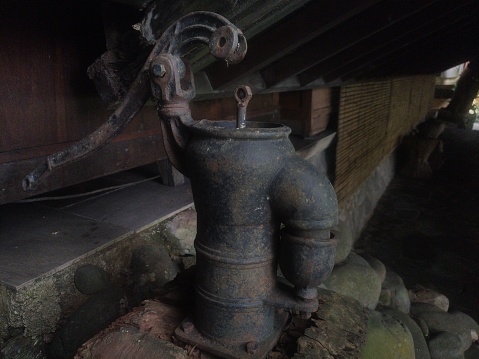 super dark, a very old traditional water pump, made of bronze, the former colonial era, belonging to an inland tribe,