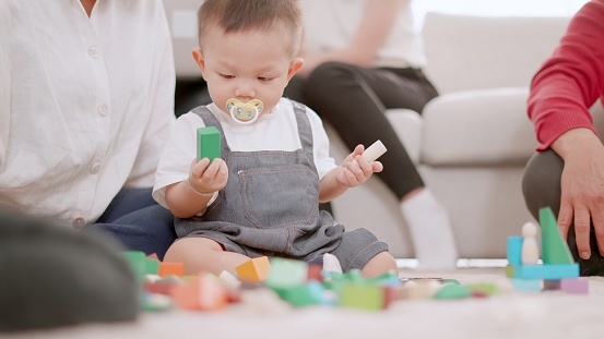 Concept of multigenerational family, life Insurance. Grandparents and young parents and children are doing activities together at cozy home, playing toys, show family love. Care and connection, Family authentic happy moments, enjoying their lifestyle.