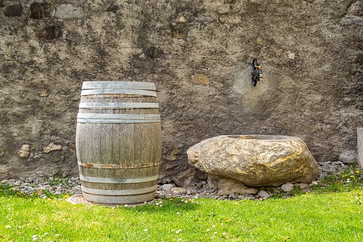 A wooden barrel set against a backdrop of stone and grass