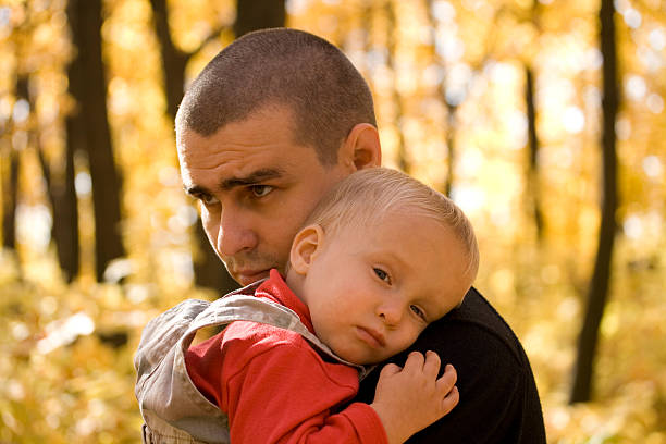 A man holding a baby with a blurry tree background stock photo