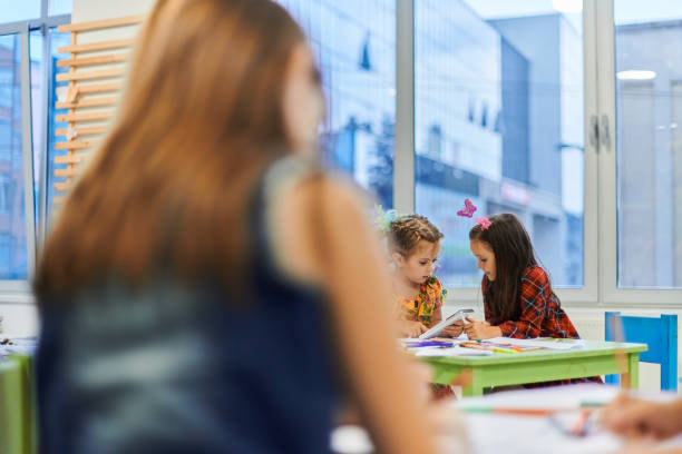 istock Creative kids during an art class in a daycare center or elementary school classroom drawing with female teacher. 1490544300
