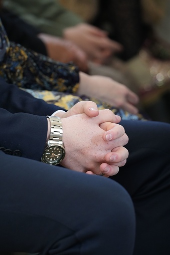 A closeup of a businessman in formal attire sitting hands clasped