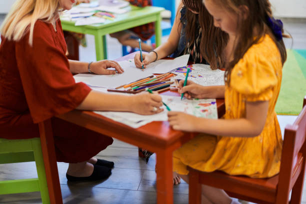 istock Creative kids during an art class in a daycare center or elementary school classroom drawing with female teacher. 1490546334
