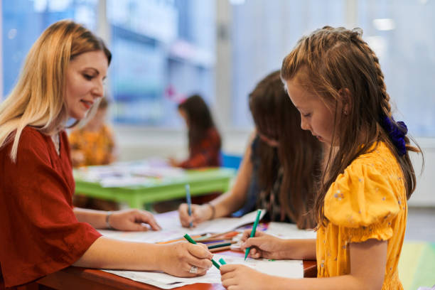 istock Creative kids during an art class in a daycare center or elementary school classroom drawing with female teacher. 1490546552