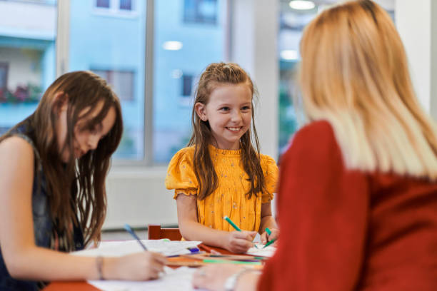 istock Creative kids during an art class in a daycare center or elementary school classroom drawing with female teacher. 1490547502