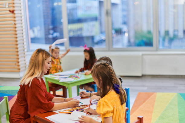 istock Creative kids during an art class in a daycare center or elementary school classroom drawing with female teacher. 1490547610