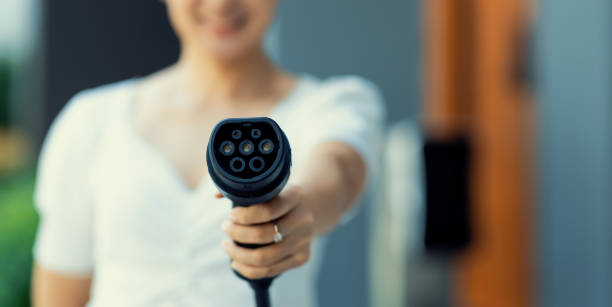 istock Focus hand pointing EV charger plug at camera with progressive blur background. 1490548191
