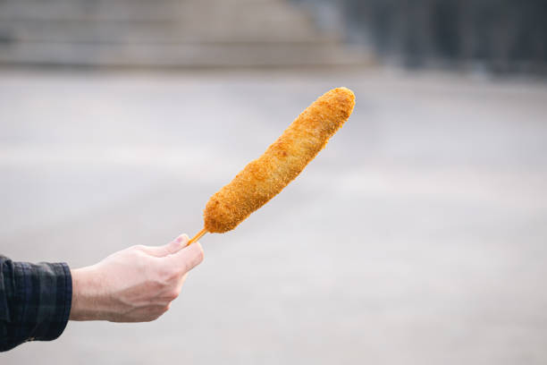Hand holding a tasty corn dogs on a blurred city background.